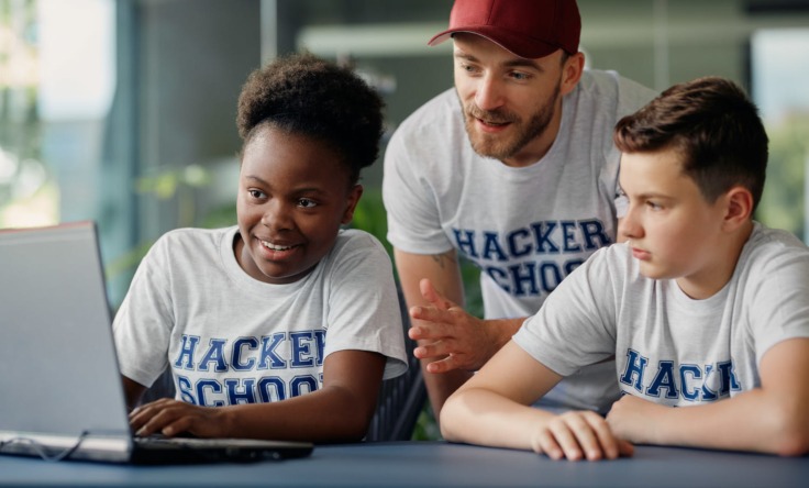Mann hilft Kindern beim programmieren