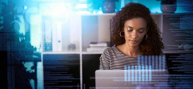 Frau sitzt an ihrem Laptop und ist im Code vertieft