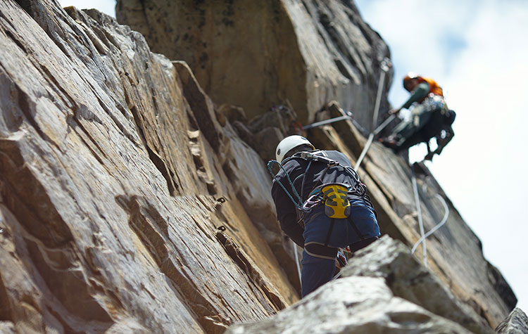 Zwei Männer klettern mit Seilen an einer Felswand