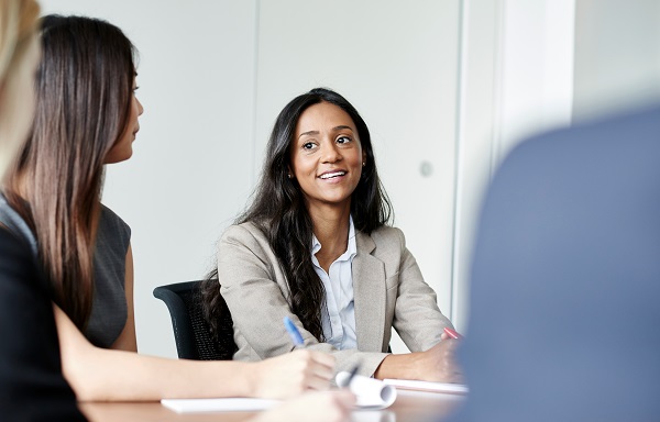 A businesswoman is actively participating in a meeting introducing herself.