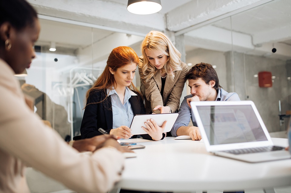 Three employees are looking at a tablet