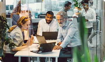 Four employees working together in a glass meeting room