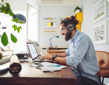 Junger Mann sitzt im Home Office an seinem Laptop und arbeitet motiviert