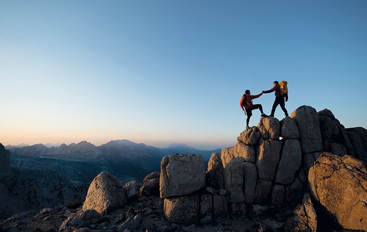 Männer helfen sich gegenseitig beim Bergsteigen