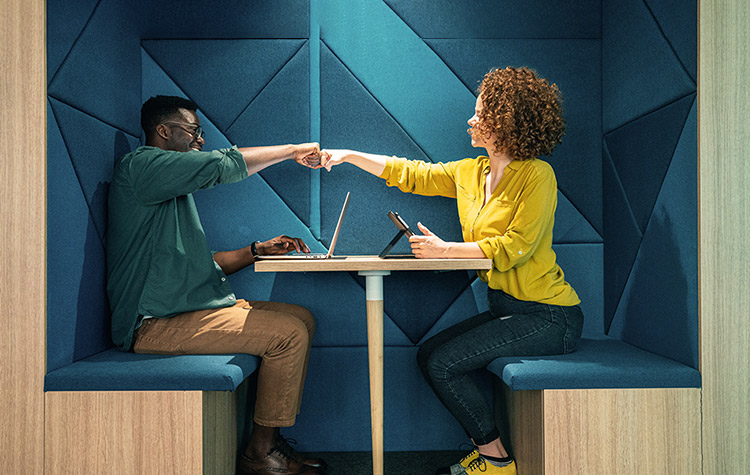 Kollege und Kollegin geben sich einen Fist Bump
