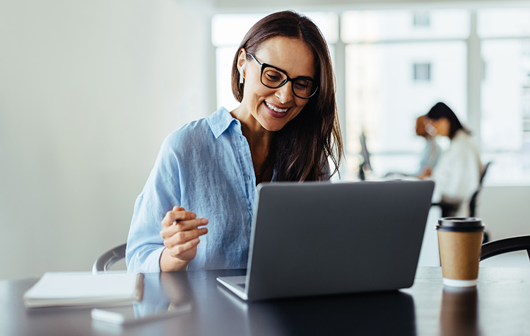 Frau arbeitet lächelnd am Laptop