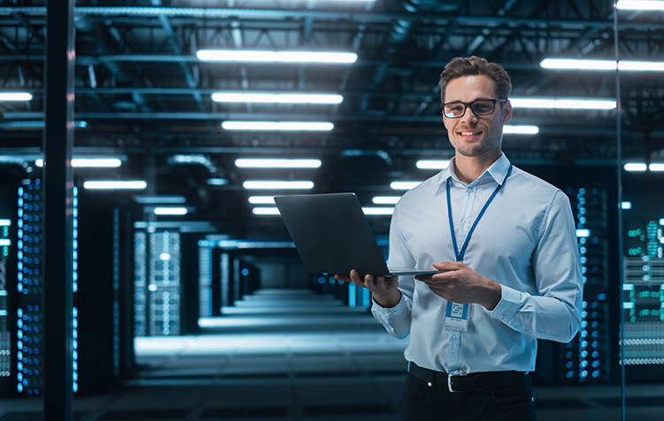 Junge IT Consultant steht in einem großen Serverraum