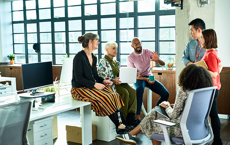 Various employees sit together casually in the office and chat