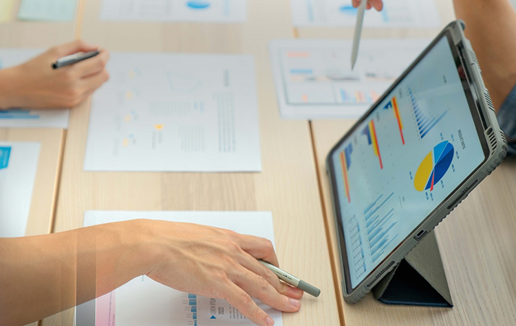 Frau sitzt vor Tablet und schaut auf Graphen