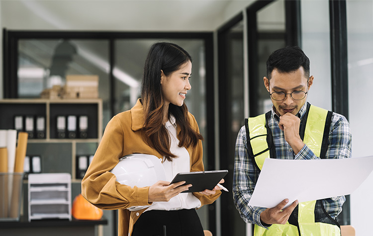 Two employees look at a plan