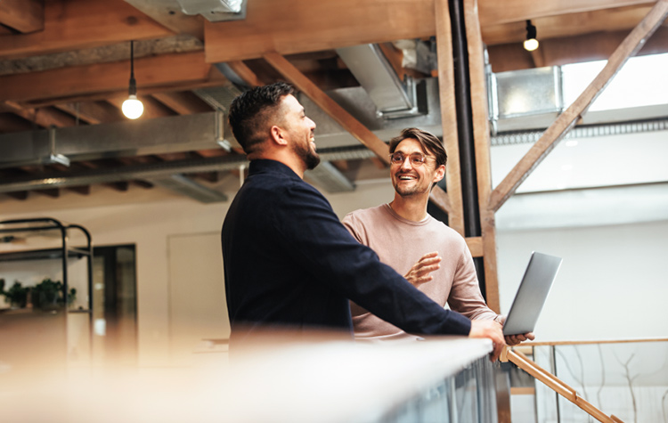 Zwei Kollegen unterhalten sich fröhlich im Foyer