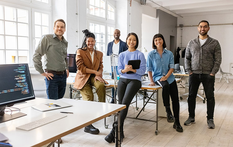 Mitarbeitende stehen zusammen im Großraumbüro