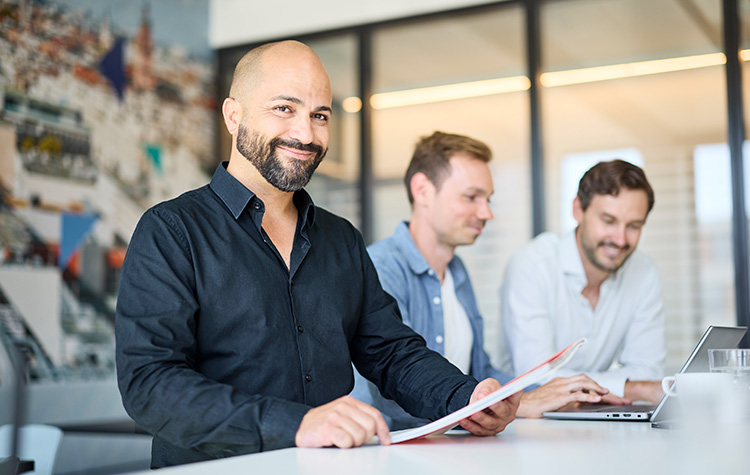 3 Mitarbeitende arbeiten im stehen nebeneinander