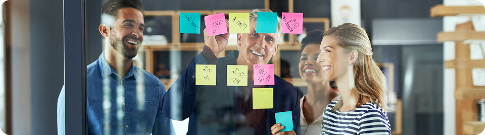 Drei Kollegen schauen sich Post its an und lachen