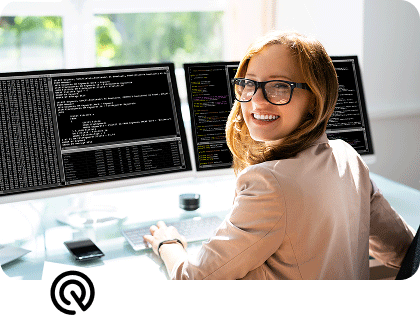 Eine Frau arbeitet am PC und lächelt in die Kamera