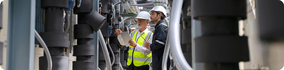 Zwei Männer mit Arbeitshelmen prüfen Maschinen