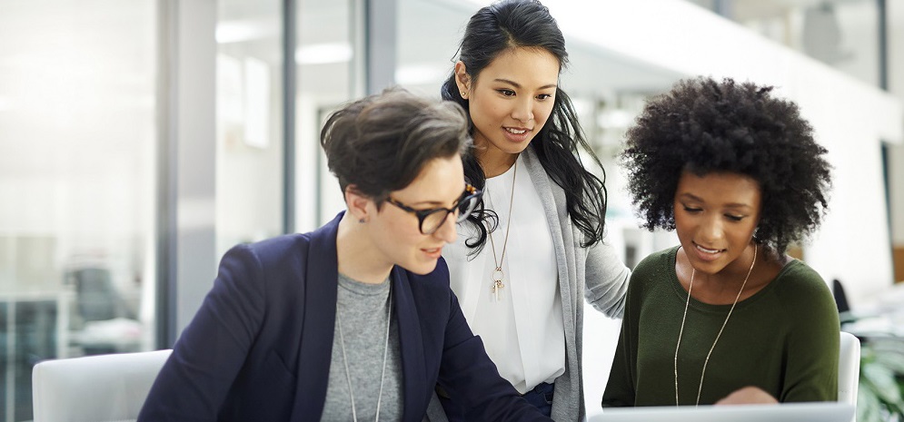 Drei Kolleginnen schauen sich zusammen etwas an