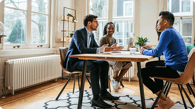 4 Freunde sitzen zusammen an einem Esstisch und unterhalten sich