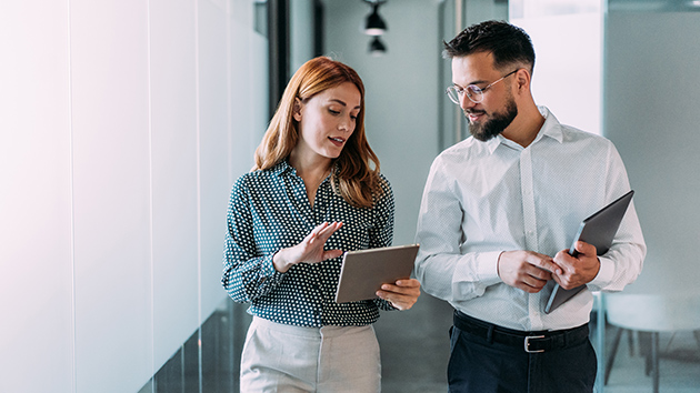 Kollege und Kollegin unterhalten sich laufend auf dem Flur