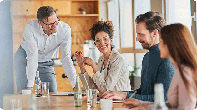 4 Mitarbeitende sitzen am Tisch und unterhalten sich