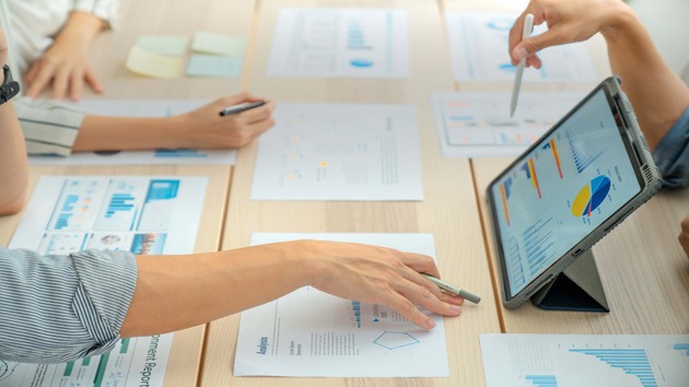 Hände auf einem Tisch, welche mit Projektunterlagen arbeiten