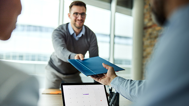Junger Mann überreicht seine Bewerbungsmappe