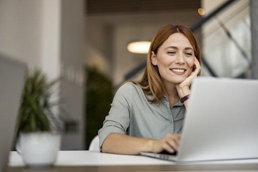Frau schaut lächelnd auf ihren Laptop