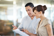 Mitarbeitende stehen nebeneinander und schauen gemeinsam auf Dokumente